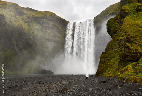 a person standing in front of Skogafoss waterfall iceland