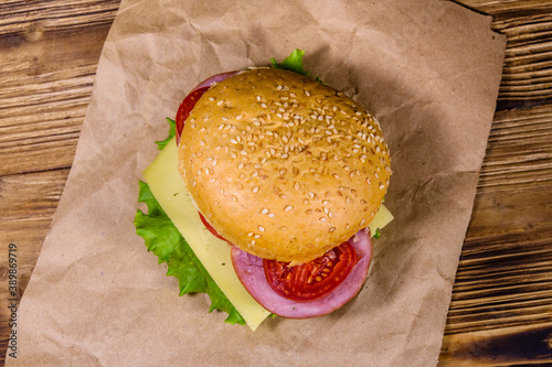 Fresh hamburger on brown paper on wooden table