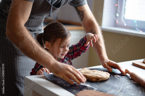 Father and little daughter cooking Christmas cookies at home. Merry Christmas and Happy Holidays.