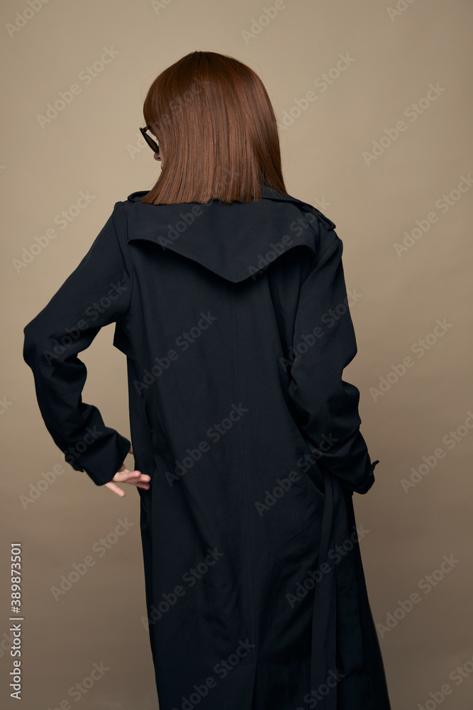 Attractive model coat with belt bright makeup having fun on a beige background 