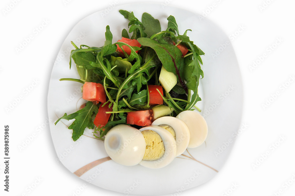 Fresh vegetable salad with egg, tomatoes, cucumbers and arugula on a plate isolated on a white background. Top view.Selective focus.