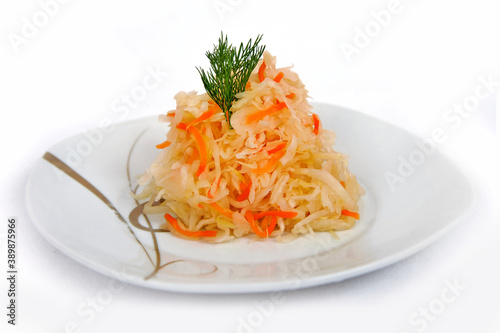 Mixed salad of home sauerkraut with carrots and spices on a plate isolated on a white background.