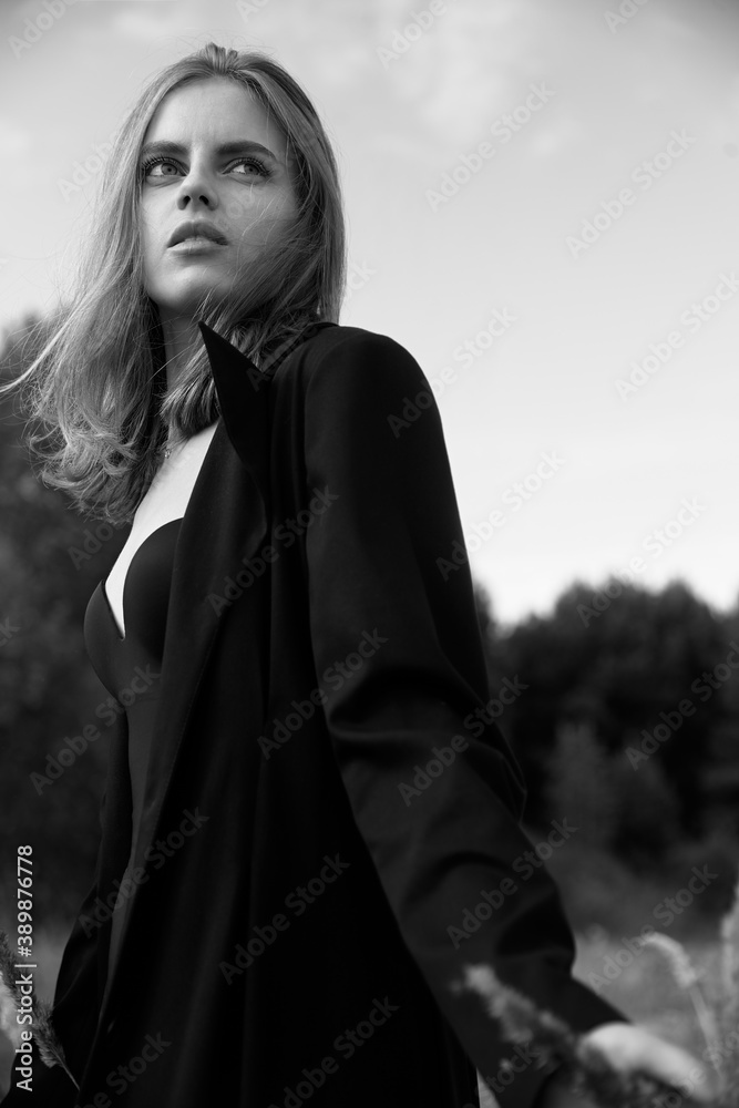 Naklejka premium Young beautiful girl walking. Summer landscape,good weather. Beach, sea. Windy day with sun and clouds. Cotton black dress eco style. Nature and freedom. Follow me. Long hair, big eyes and lips