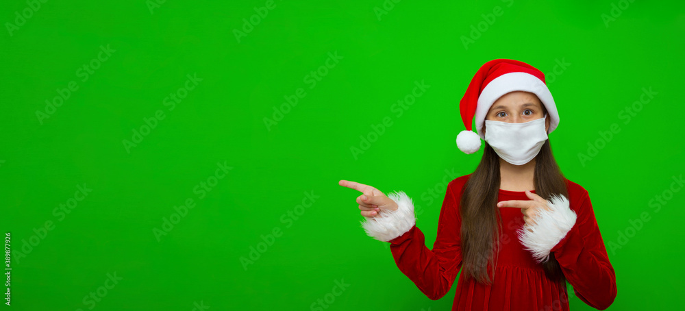 A girl with dark hair dressed as a miss claus in a Santa hat points her finger towards the place for advertising. Banner. A girl with dark hair dressed as a miss claus in a Santa hat points her finger towards the place for advertising. Banner.