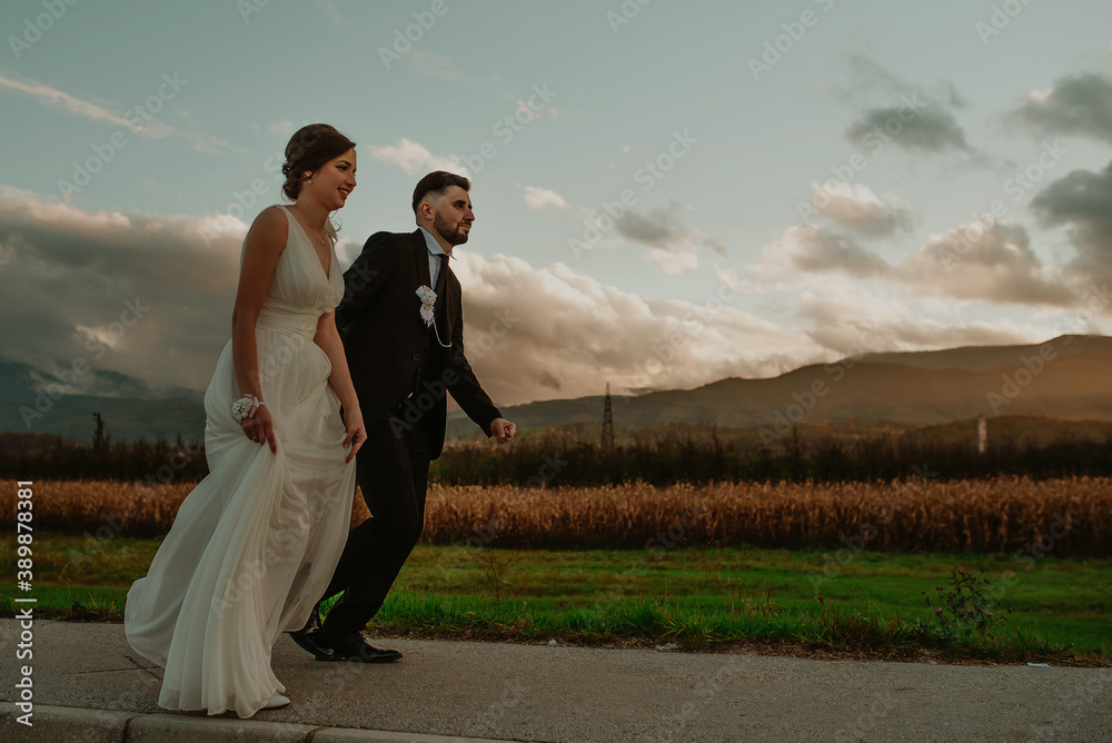 Affectionate bride and groom, holding hands, happily run down the street Affectionate bride and groom, holding hands, happily run down the street
