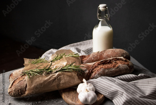 Wheat bread, garlic and a bottle of milk on the table.