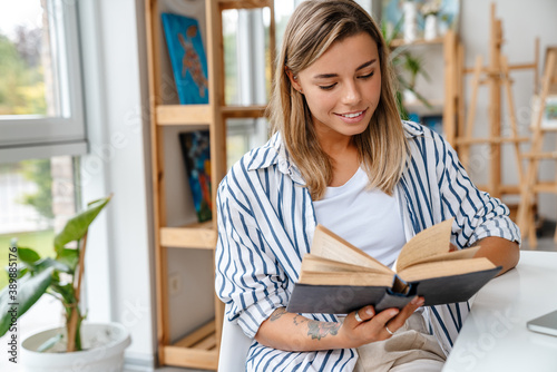 Smiling attractive young woman designer reading book