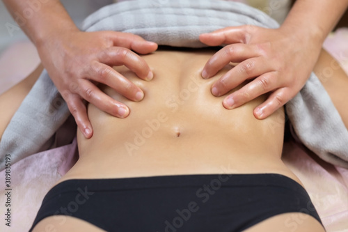 Caucasian young woman having stomach massage during spa treatment.