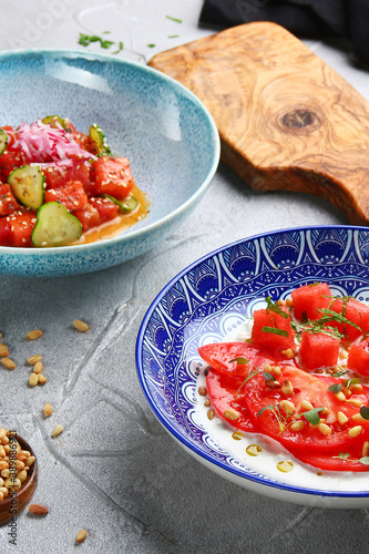 stracciatella salad with tomatoes and watermalone and ingredients on light concrete table