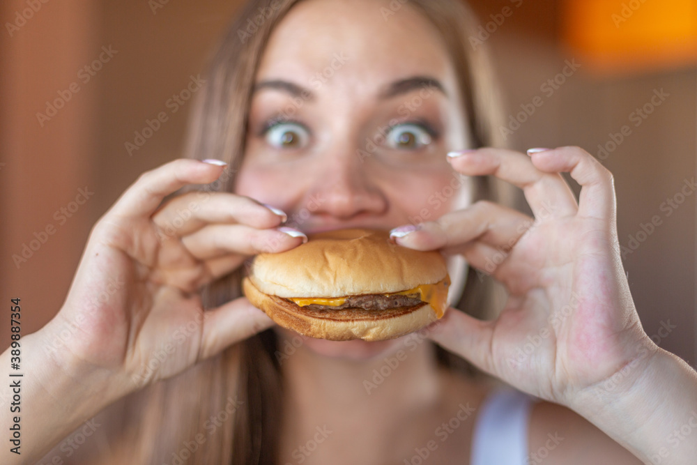 Close up of beautiful hungry young brunette is about to bite a delicious hamburger. Concept of junk food and fast food