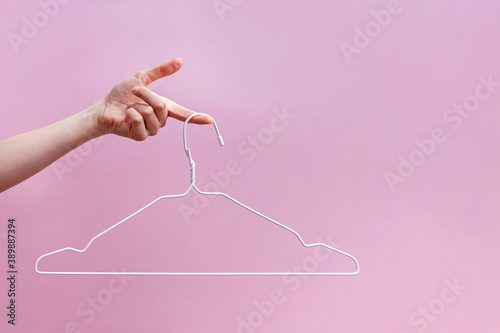 Feminine hand holding empty hanger isolated on pink background photo