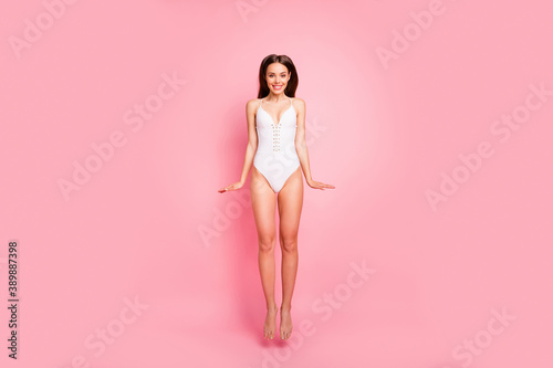 Full body photo of funny lady jumping smiling dressed swimwear isolated over pink background