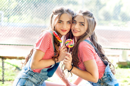 Portrait of two beautiful girls twins with lollipop