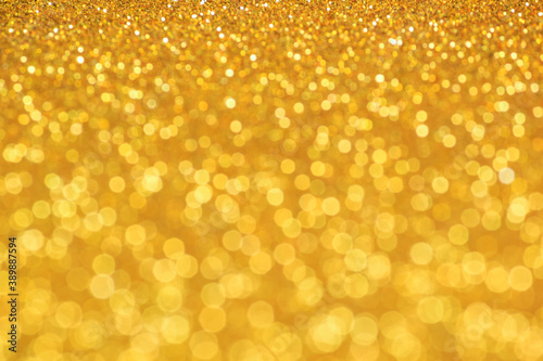 Golden glittering background. Sparkle glitter texture with the bokeh and the lights, shiny metal gold foil