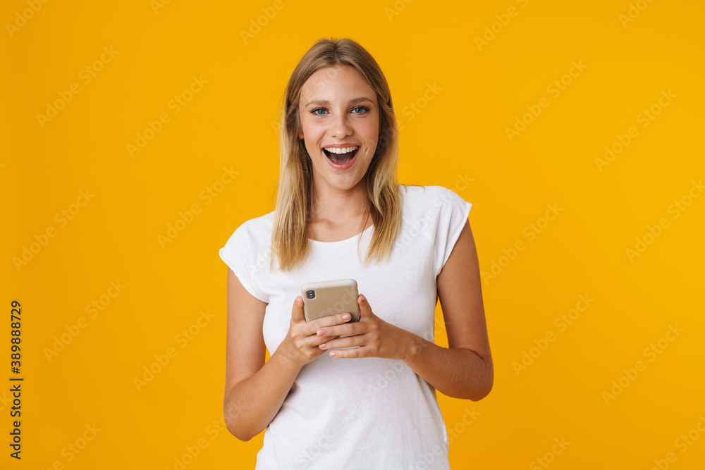 Excited blonde girl smiling and using mobile phone Excited blonde girl smiling and using mobile phone