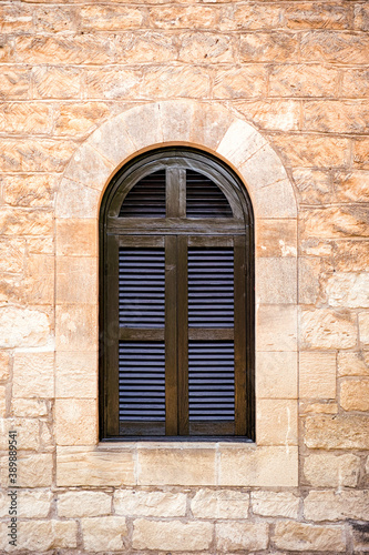 Arched window with closed shutters on stone wall