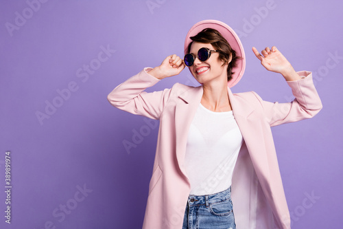 Photo of nice positive brunette hair young lady dance wear cap coat look empty space isolated on violet color background
