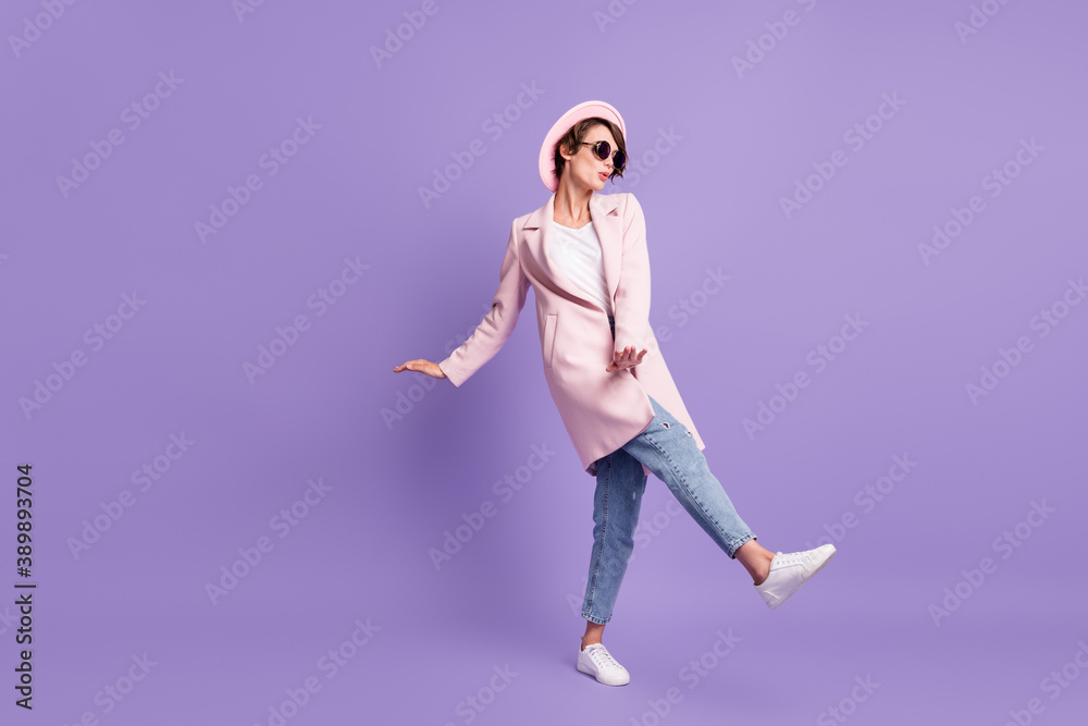Full size photo of dancing nice cool girl look empty space sing wear glasses coat cap jeans footwear isolated on purple background