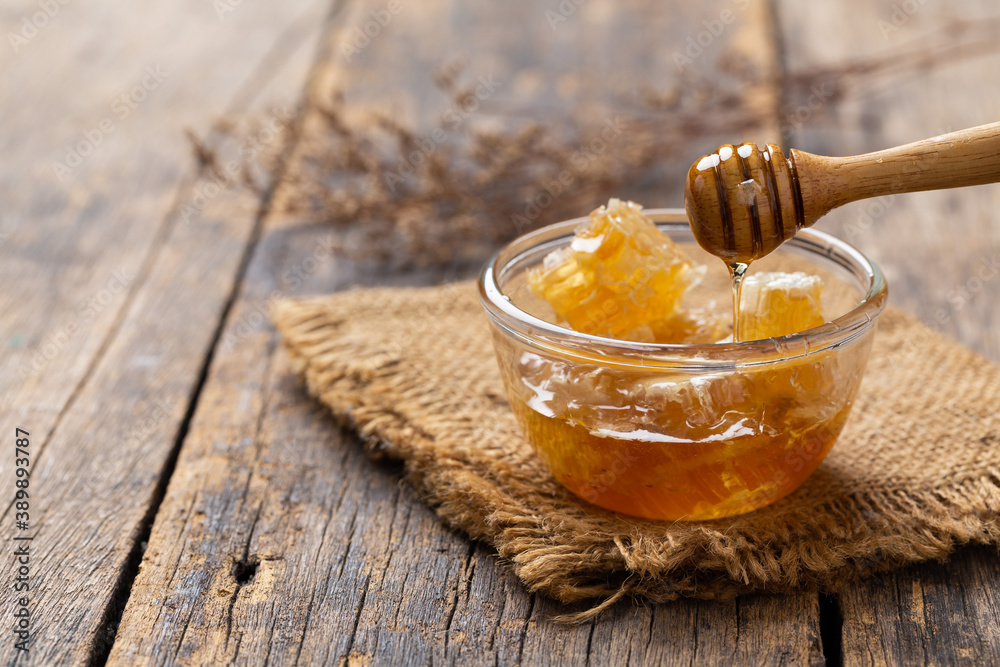 Honey In a glass cup and a honeycomb On a wooden background Honey In a glass cup and a honeycomb On a wooden background