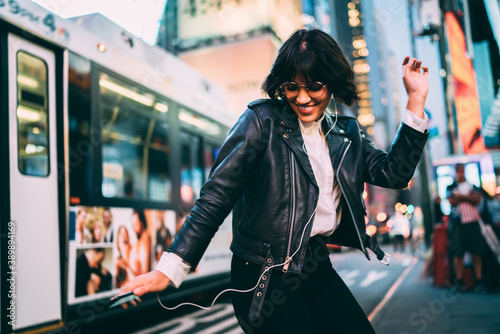 Photography Carefree woman in fashionable clothing listening funny audio and dancing during