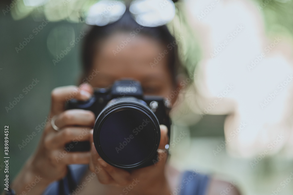 Lifestyle portrait of a Woman photographer taking photo by digital camera. Selective focus at lens, unrecognizable person