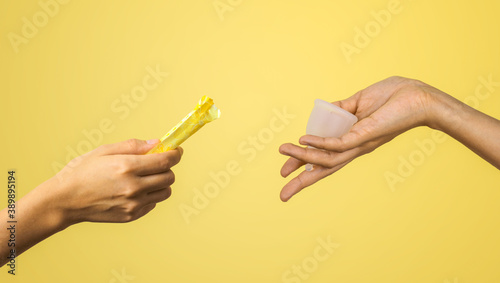 Zero waste alternative consept. Tampon vs menstrual cup. Woman hands on pastel yellow background. hygiene period product.