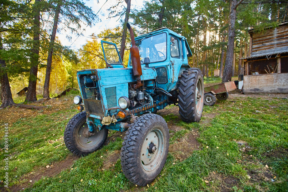 An old blue tractor stands in a farmyard An old blue tractor stands in a farmyard