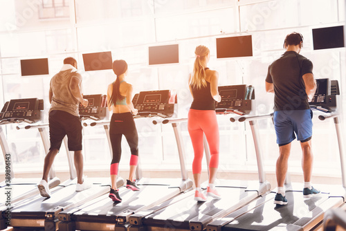 Fototapeta Naklejka Na Ścianę i Meble -  People athletes on treadmills run together
