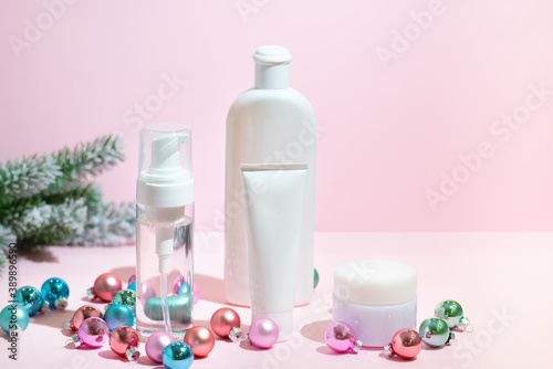 Christmas beauty skin care cosmetic products with decoration balls on the pink background