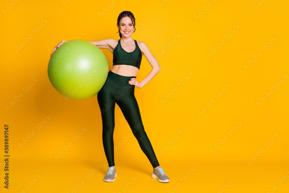 Fototapeta premium Full length body size view of nice attractive healthy cheerful girl carrying pilates fitness ball posing isolated over bright yellow color background.