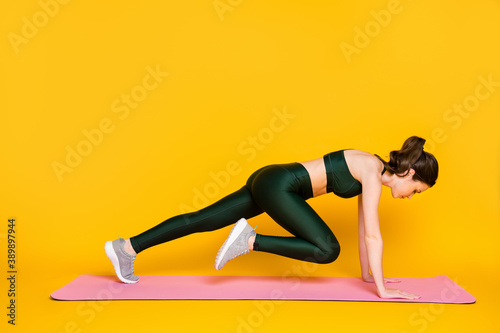 Profile side full body view of attractive slender sportive girl doing everyday work out striving isolated on bright yellow color background