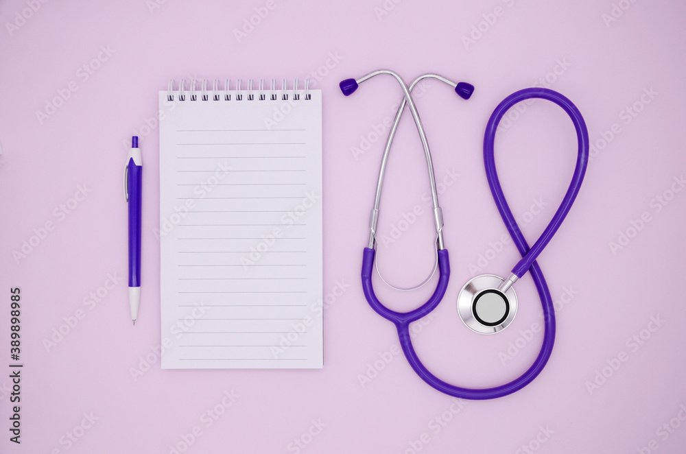 Stethoscope, Notepad and pen on a pink background with copy space. Medical flat lay.