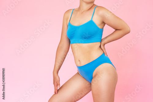 Slim woman in blue underwear on pink background