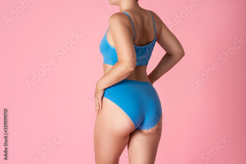 Slim woman in blue underwear on pink background