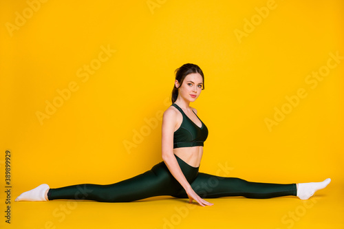 Photo of sportive young lady sitting floor split legs flexibility wear suit top pants socks isolated yellow color background
