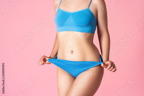 Slim sexy woman in blue underwear on pink background