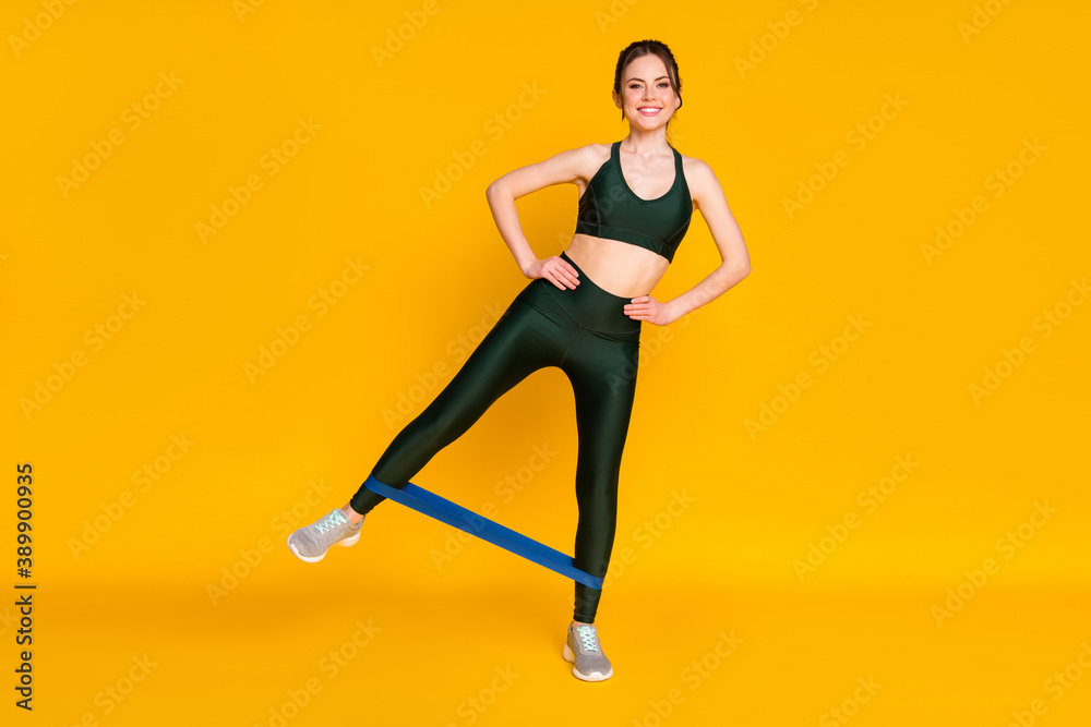 Lady practicing house gym training stretch rubber stripe wear sports suit isolated yellow color background
