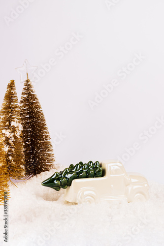 Christmas composition. White toy car carrying christmas tree in a snow forest. New Year minimal concept with copy space
