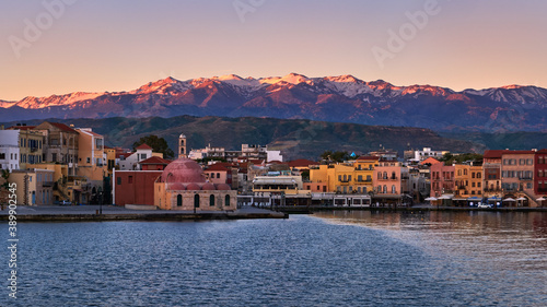 Sunrise view of Old Venetian harbour of Chania, Crete, Greece, its quay side. Great Cretan mountains covered with snow. Former mosque Giali Tzamisi