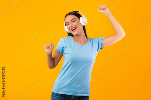 Smiling lady enjoying music with headphones and dancing © Prostock-studio