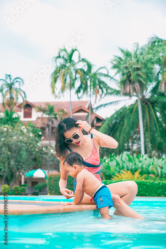 Asian mother and little son enjoying swimming in a swimming pool in summer vacation. © grooveriderz