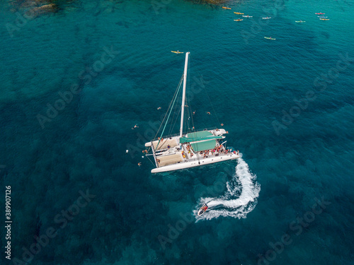 Aerial view of a catamaran with people on board and in the sea, swimming near the coasts of the island of Lanzarote, Canary, Spain. Jet ski performing in the sea  © Naeblys