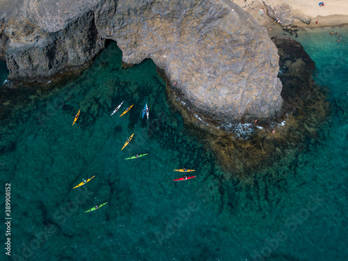 Aerial view of canoes sailing near the rugged coastlines and beaches of Lanzarote, Spain, Canaries. Explore the island. Bathers on the beach and in the Atlantic Ocean. Papagayo