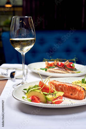 A glass of wine and fish dishes in a restaurant.