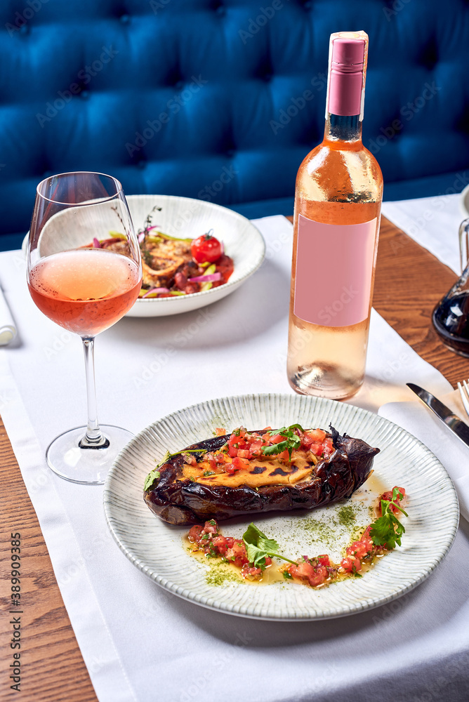 A bottle of wine and a dish of zucchini in a restaurant.