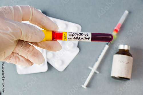 Covid - 19 negative blood test sample in doctors hand whit white glove, vaccine ampule and needle