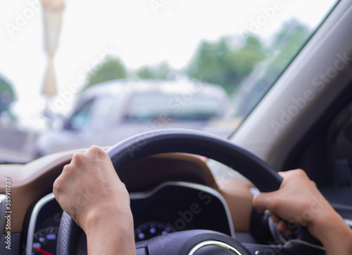 Female hands on the steering wheel of a car while driving.Close-up of a woman's hand driving a car.