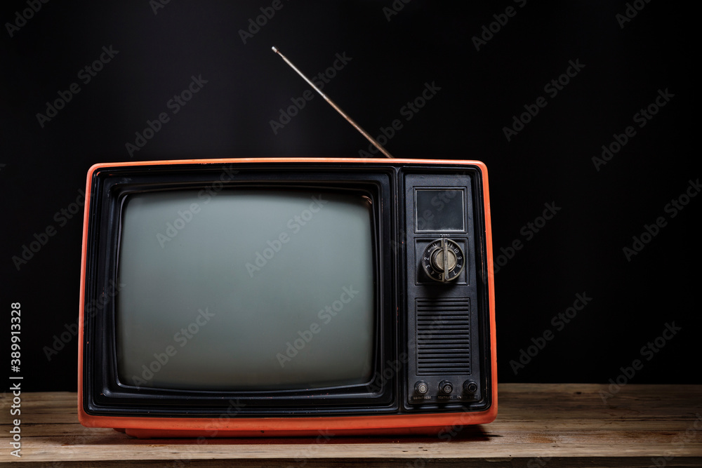 Retro old TV on wooden table in room with black background