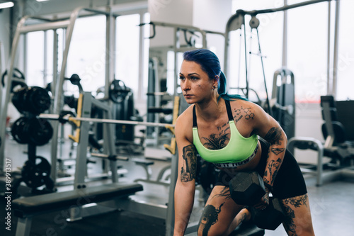 Fotografija tattooed young woman exercising in the gym