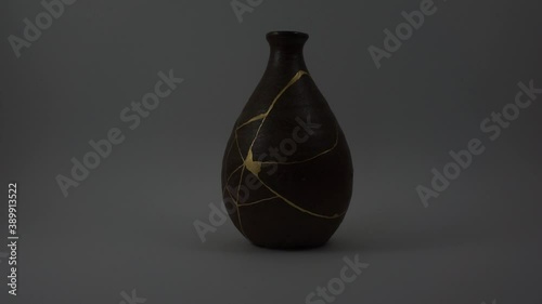 Kintsugi bizen sake bottle. Bright gold cracks lighted up. Fragile cracks trauma representation. Psycology. photo